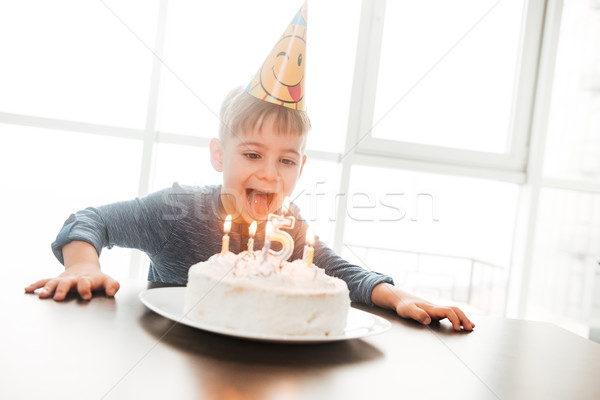 Happy birthday boy sitting in kitchen near cake Stock photo © deandrobot