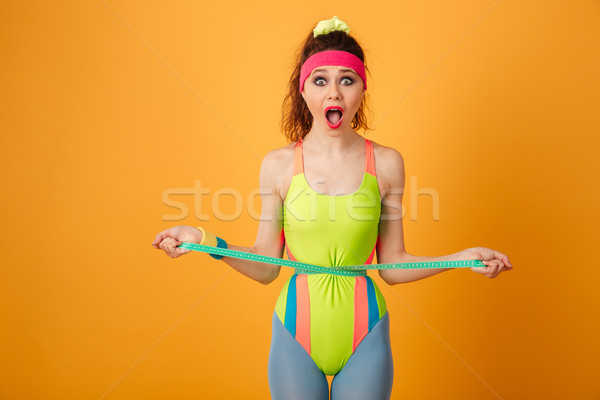 Shocked surprised fitness woman standing and measuring waist with tape Stock photo © deandrobot