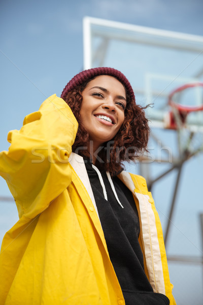 Smiling african curly young lady wearing yellow coat Stock photo © deandrobot
