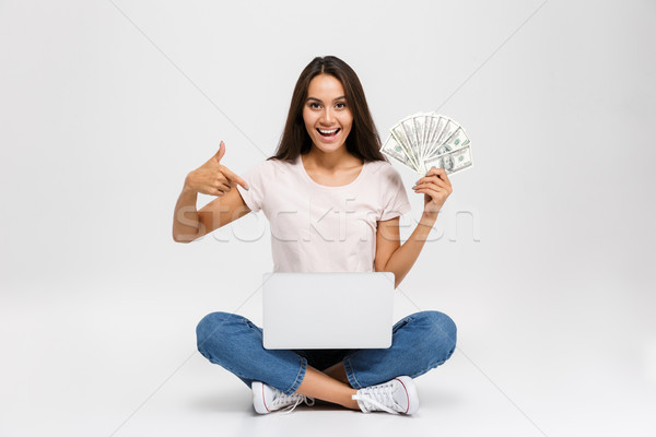Portrait of an excited satisfied asian girl holding money banknotes Stock photo © deandrobot