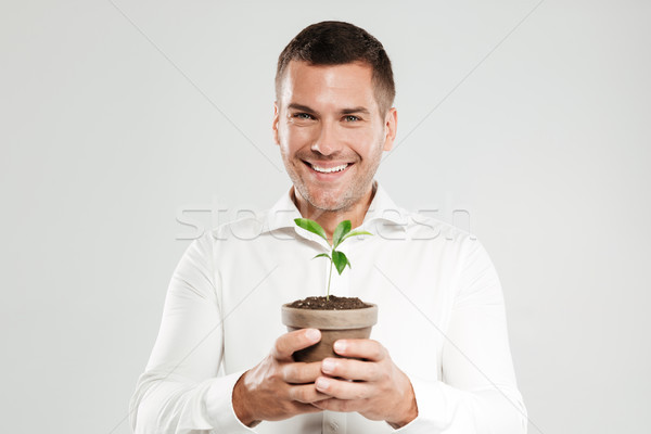 Smiling man holding plant. Stock photo © deandrobot