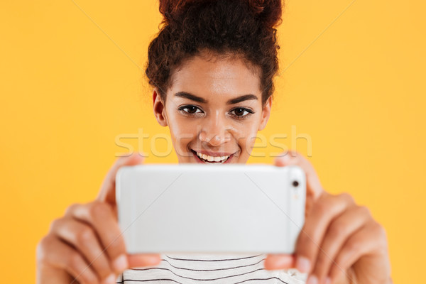 Close-up portrait of smiling african woman making photo on smartphone Stock photo © deandrobot
