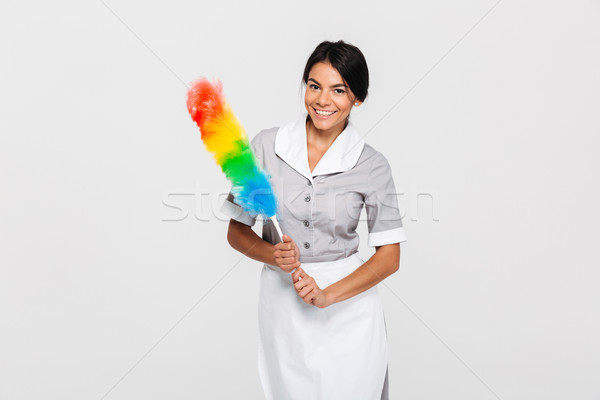 Cheerful maid in uniform holding colorful duster while standing  Stock photo © deandrobot