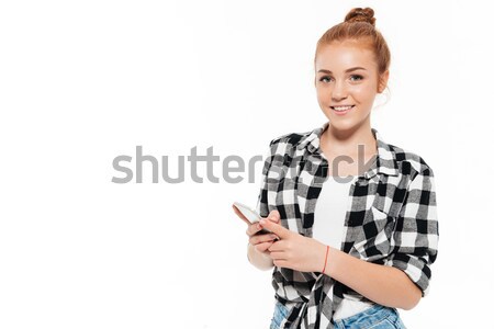 Happy ginger woman in shirt and jeans holding smartphone Stock photo © deandrobot
