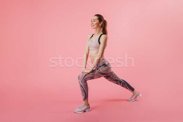 Full length side view image of Pleased sportswoman doing exercise Stock photo © deandrobot