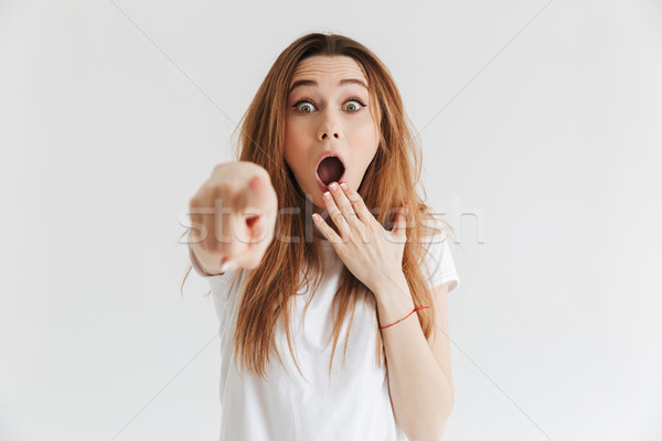 Shocked woman in t-shirt pointing at camera and covering mouth Stock photo © deandrobot
