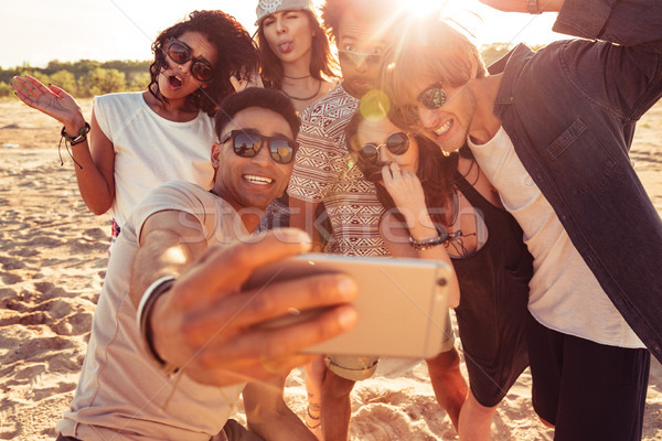 Excited young friends on the beach make selfie Stock photo © deandrobot