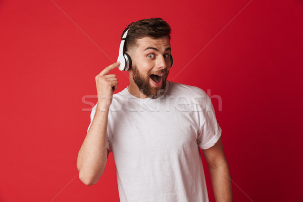 Shocked young man isolated listening music with headphones. Stock photo © deandrobot