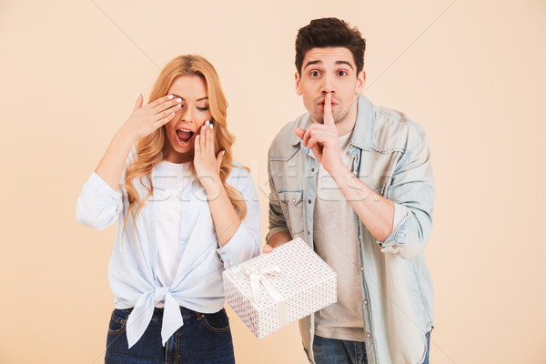 Stock photo: Image of young man with present box keeping finger at lips and a