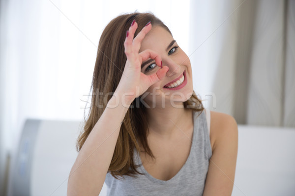Happy woman looking through fingers at home Stock photo © deandrobot