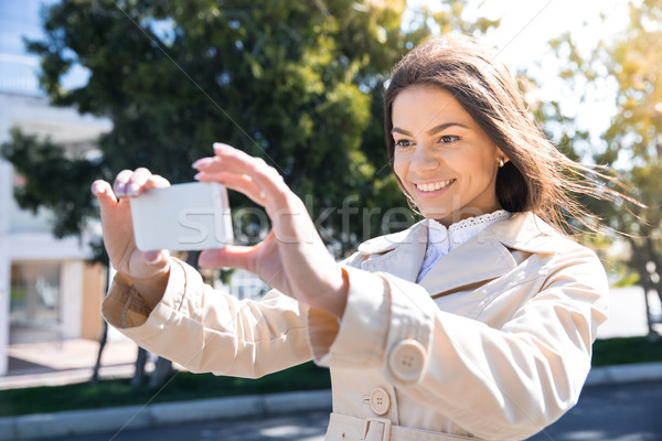 Smiling woman making photo on smartphone Stock photo © deandrobot