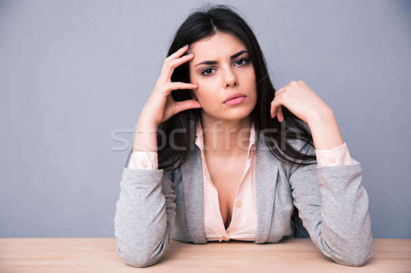 Sérieux jeune femme séance table gris regarder [[stock_photo]] © deandrobot