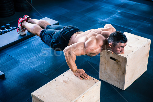 Muscular man doing push ups on fit box Stock photo © deandrobot