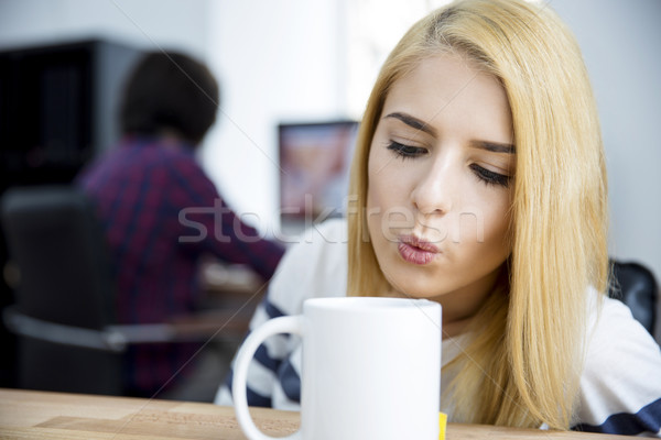 Woman blowing on a mug of hot coffee Stock photo © deandrobot