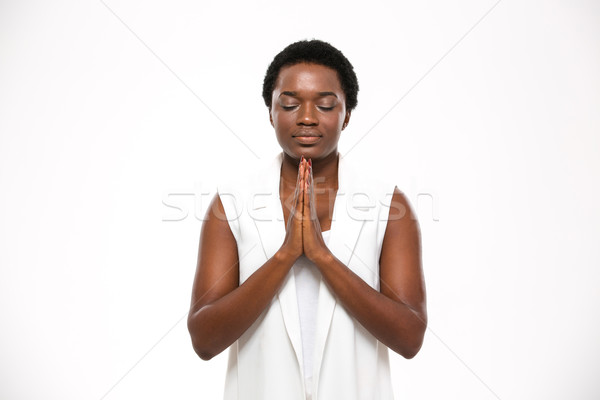 Calm pretty african woman with closed eyes standing and meditating Stock photo © deandrobot