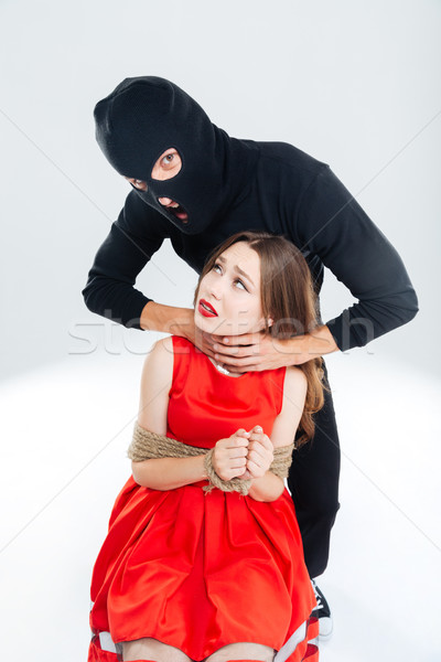 Scared woman bounded with ropes choking by man in balaclava Stock photo © deandrobot