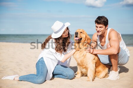 Young stylish couple in love sitting playing with dog Stock photo © deandrobot