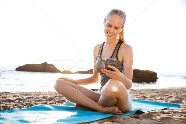 Woman doing yoga and using cell phone sitting on mat Stock photo © deandrobot