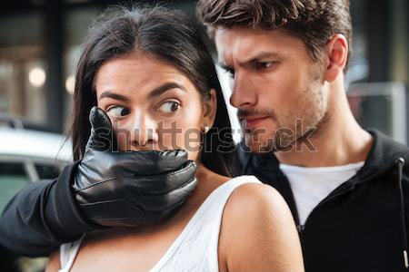 Robber covered mouth of woman and threatening with gun outdoors Stock photo © deandrobot
