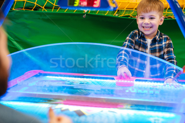 Cheerful little boy playing air hockey at indoor playground Stock photo © deandrobot