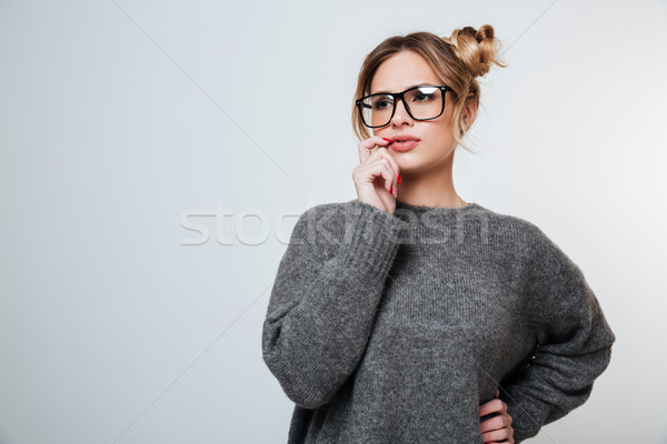 Stock photo: Pensive beautiful young woman in glasses standing and thinking