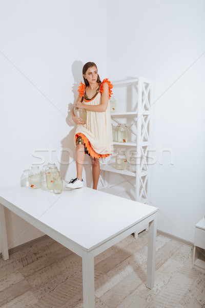 Woman standing on table and holding gold fish in jar Stock photo © deandrobot