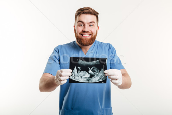 Portrait of a smiling young male medical doctor showing radiograph Stock photo © deandrobot