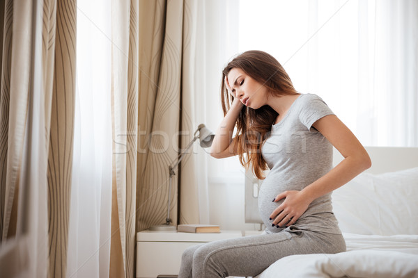 Stock photo: Sad pregnant woman having headache and feeling sick on bed