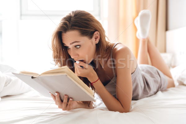 Shocked pretty lady lies on bed indoors Stock photo © deandrobot