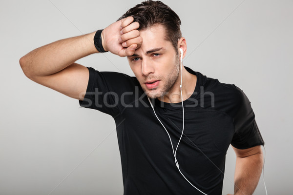 Portrait of a young tired sweaty sportsman in earphones Stock photo © deandrobot