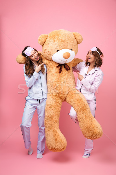 Friends women in pajamas with teddy bear pointing Stock photo © deandrobot