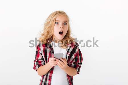 Portrait of a shocked little girl holding mobile phone Stock photo © deandrobot