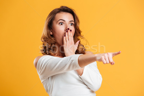 Shocked young woman pointing. Stock photo © deandrobot