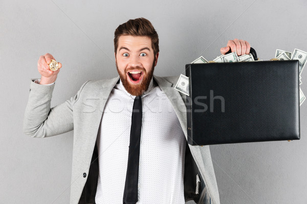 Portrait of a happy businessman showing golden bitcoin Stock photo © deandrobot