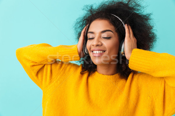Adorable american smiling woman in yellow shirt listening to mus Stock photo © deandrobot