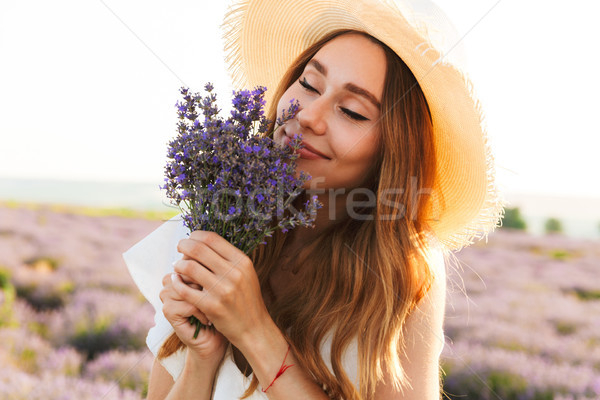 Cheerful young girl in straw hat smeling lavender bouquet Stock photo © deandrobot