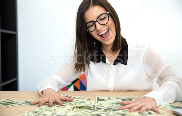 Surprised young businesswoman sitting at the table with money Stock photo © deandrobot