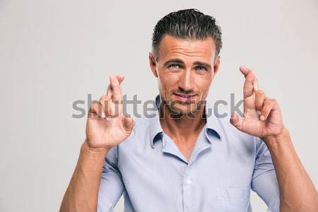Jóképű férfi kereszt ujjak portré szürke néz Stock fotó © deandrobot