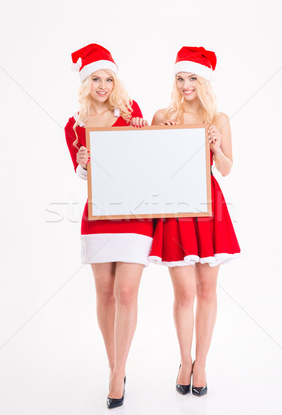 Two cheerful sisters twins posing with blank board  Stock photo © deandrobot