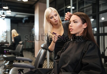 Mirror reflection of young woman getting her hairdo by stylist Stock photo © deandrobot