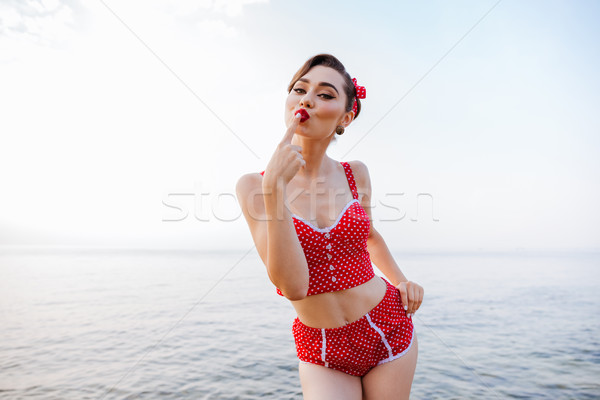 Happy pretty pinup girl in red swimsuit sending a kiss Stock photo © deandrobot
