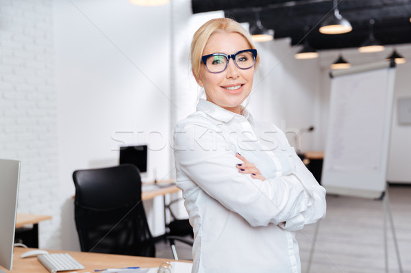 Mature business woman standing with arms folded in office Stock photo © deandrobot