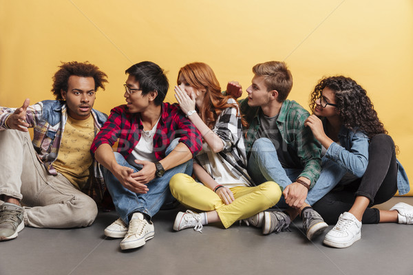 Smiling people sitting and telling secrets to their surprised friend Stock photo © deandrobot