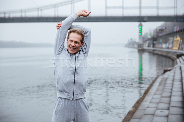 Elderly man warming up near the water Stock photo © deandrobot