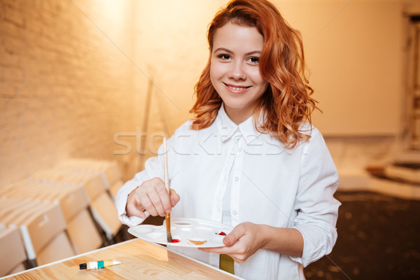 Happy redhead woman painter with paints and palette Stock photo © deandrobot
