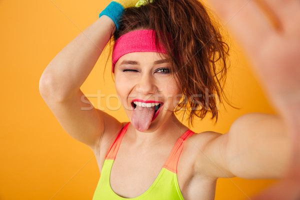 Cheerful young sportswoman making selfie, winking and showing tongue Stock photo © deandrobot