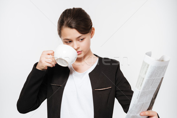 Serious young girl drinking coffee reading gazette Stock photo © deandrobot
