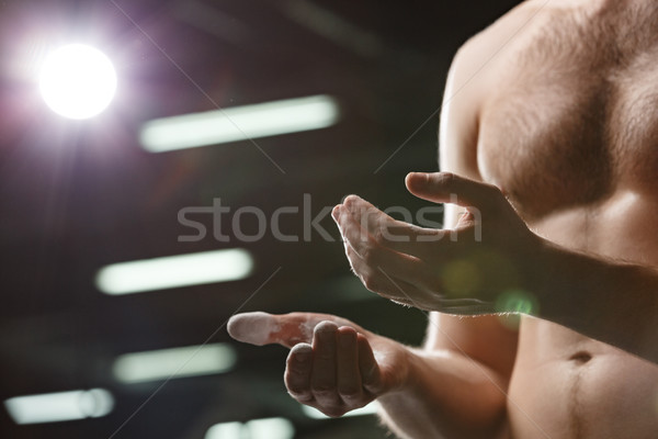 Handsome sports man in gym rubbing hands with chalk Stock photo © deandrobot