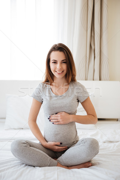 Derűs terhes nő ül ágy lábak keresztbe gyönyörű Stock fotó © deandrobot
