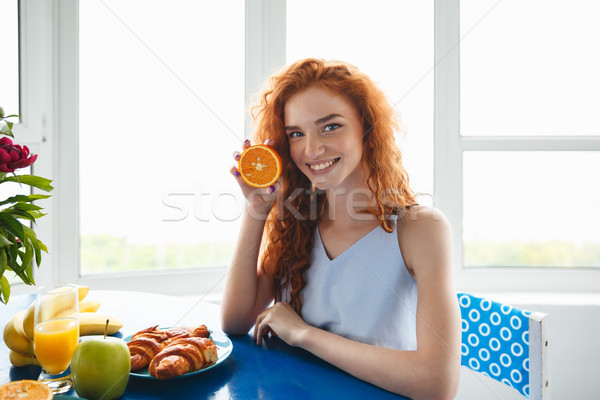Young smiling redhead lady holding orange Stock photo © deandrobot